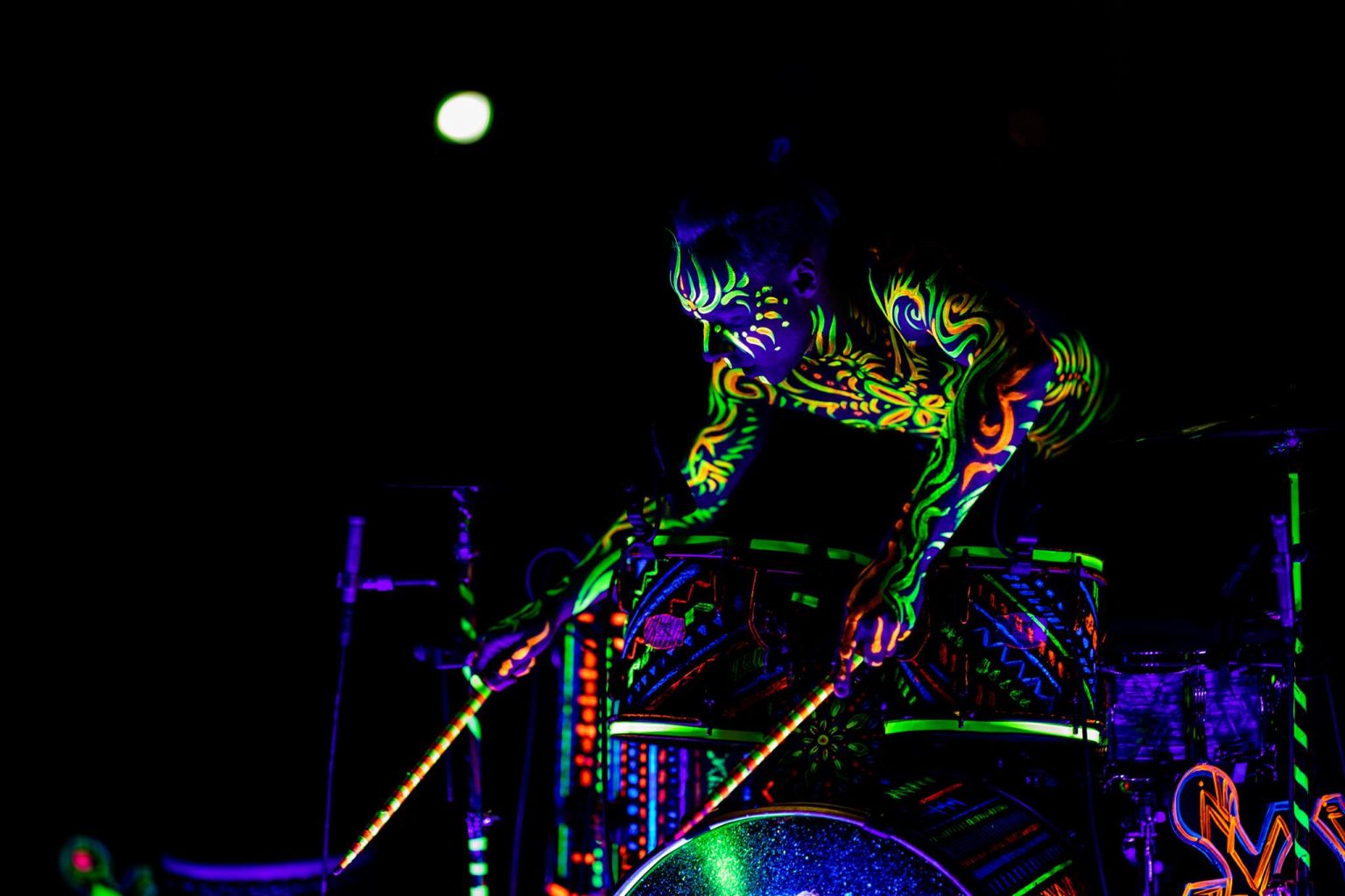 Drummer Siim Koppel playing the drums in his UV-coloured drum showl