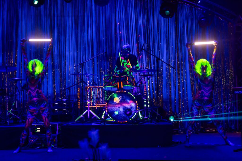 Drummer Siim Koppel playing the drums in his UV-coloured drum showl